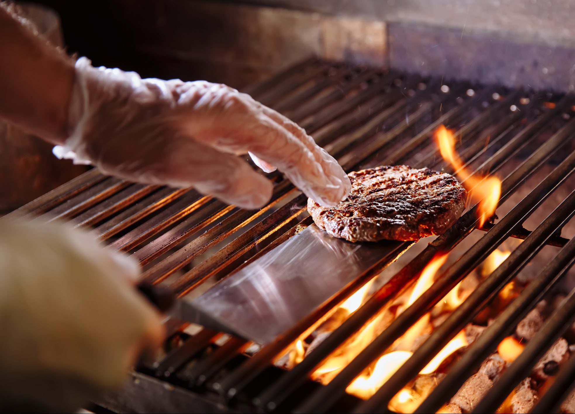 FUNIBER-chef-making-burger-beef-or-pork-meat-barbecue-burgers-for-hamburger-prepared-grilled-on-bbq-fire-flame-grill-close-up-shot-of-chefs-hands-turn-the-chop-on-the-grill