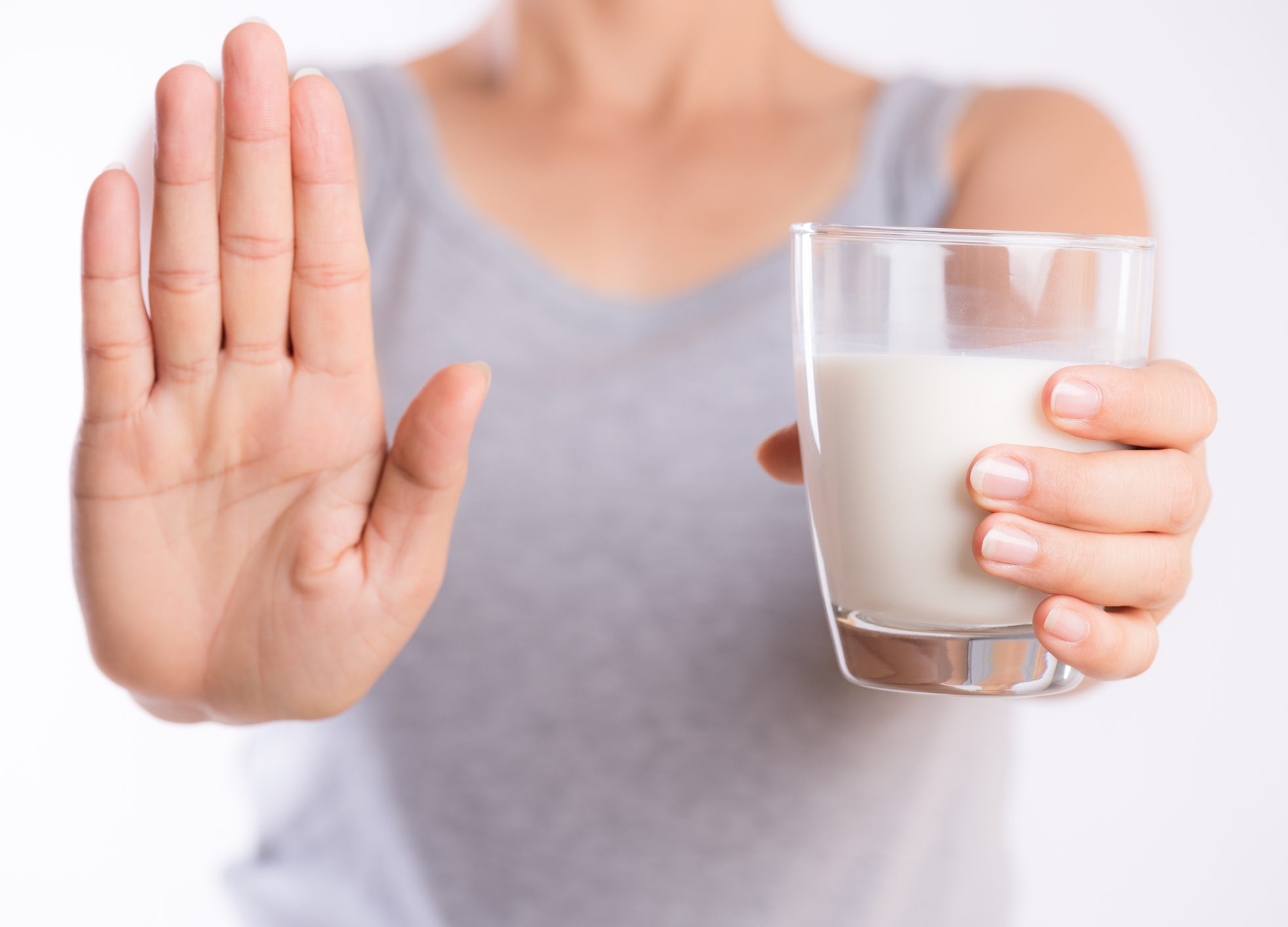 FUNIBER-woman-hand-holding-glass-of-milk-having-bad-stomach-ache-because-of-lactose-intolerance-and-another-hand-shows-stop-sign-health-problem-with-dairy-food-products-healthcare-and-medical-concept-