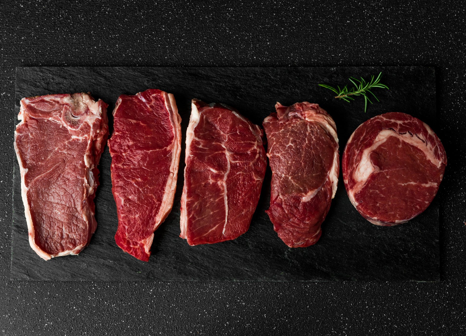 FUNIBER-selection-of-raw-beef-meat-food-steaks-against-black-stone-background-new-york-striploin-steak-top-blade-rib-eye-and-other-cuts-of-meat-