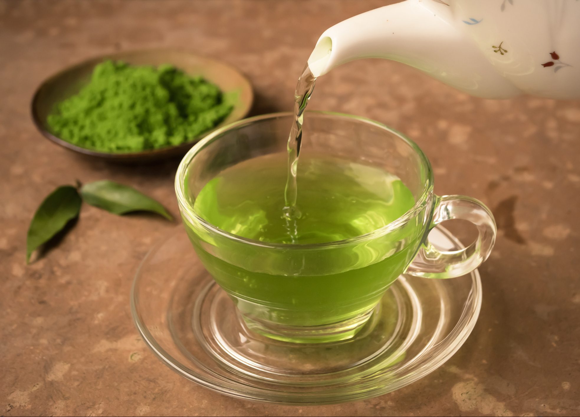 FUNIBER-green-tea-being-poured-into-glass-tea-cup-on-the-table