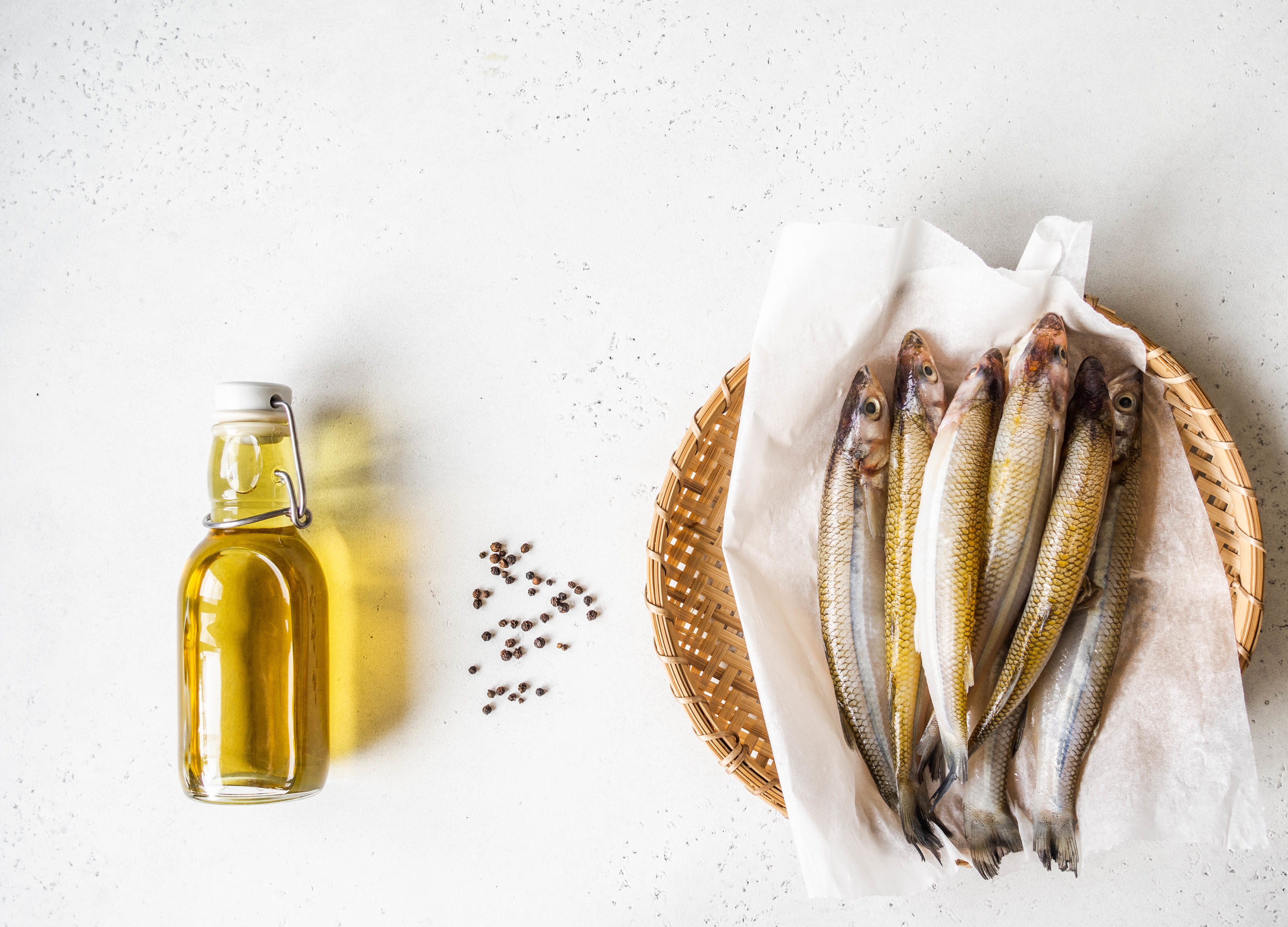 FUNIBER-fresh-raw-smelt-fish-on-wicker-tray-spice-and-olive-oil-in-bottle-on-a-wind-background-